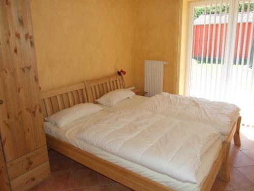 a bedroom with a bed with white sheets and a window at Ferienhaus Kajuete in Schönhagen