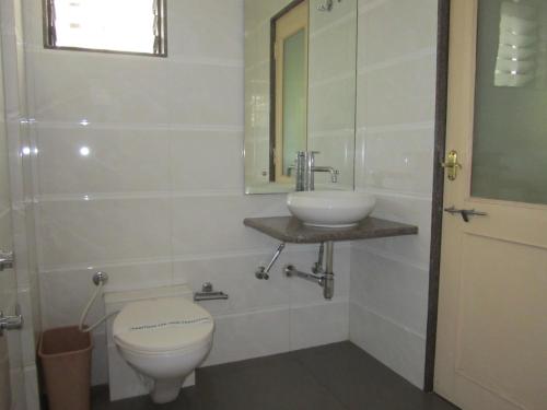 a bathroom with a toilet and a sink at Hotel Sarita in Surat