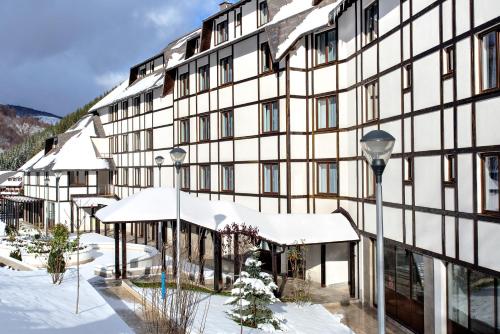 a building in the snow with snow covered roofs at Brzeće Center Apartments in Kopaonik