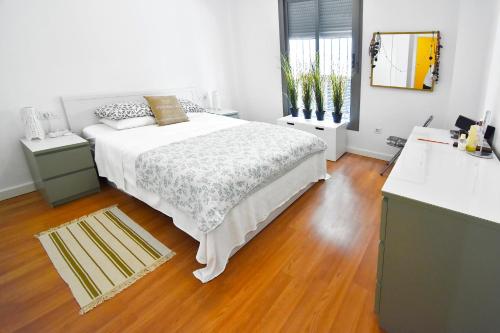 マラガにあるSerendipity Apartmentsの白いウッドフロアのベッドルーム(ベッド1台付)