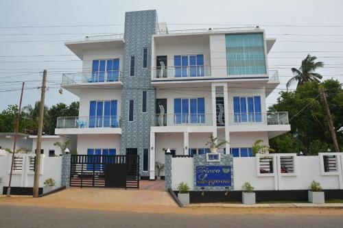 a white building with blue windows and a fence at Trinco Lagoon in Trincomalee