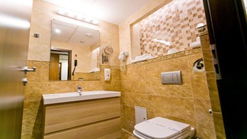 a bathroom with a sink and a toilet and a mirror at Hotel Forum in Ploieşti