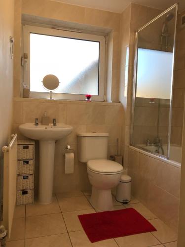 a bathroom with a toilet and a sink and a window at Cozy apartment in Stratford from 18 minutes to Central London in London