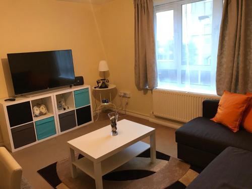 a living room with a tv and a couch and a table at Cozy apartment in Stratford from 18 minutes to Central London in London