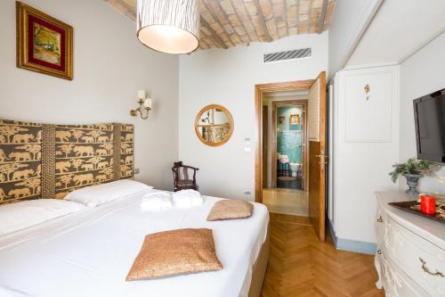 a bedroom with a bed with white sheets and a tv at Rooms Roma - Monti in Rome