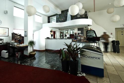 a restaurant with a counter in a room with plants at Desalis Hotel London Stansted in Elsenham