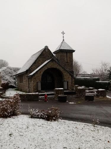 a small brick church with a cross on the roof at La Métairie in Houffalize