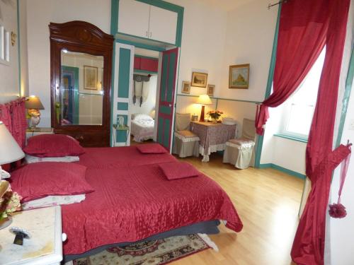 a bedroom with a large red bed with red sheets at La Demeure aux Hortensias in Pleurtuit