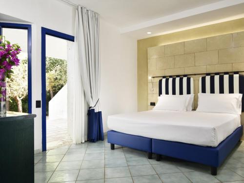 a bedroom with a large bed with blue and white pillows at TH Ostuni - Ostuni Village in Ostuni