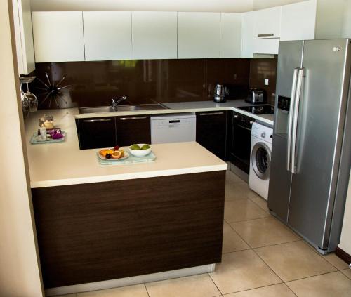 a kitchen with a refrigerator and a plate of food on the counter at Alyzes Diamant in Le Diamant