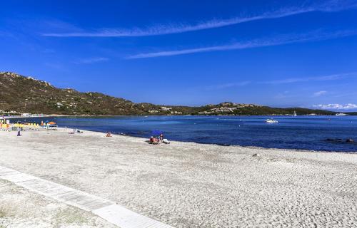 a beach with people sitting on the sand and the water at Colonna Beach Hotel Marinella in Marinella