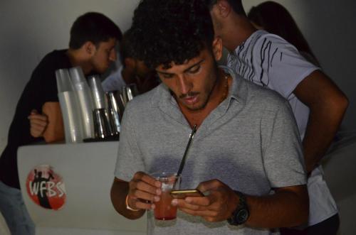 a man holding a drink and looking at his cell phone at Ostello Salento in Alezio