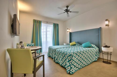 db San Antonio Hotel + Spa All Inclusive في خليج سانت بول: غرفة نوم بسرير وطاولة وكرسي