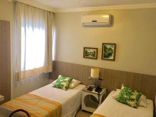 a hotel room with two beds and a window at Aldeota Praia Hotel in Fortaleza