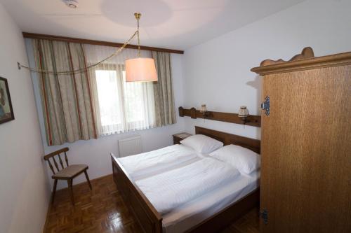 a bedroom with a bed and a chair and a window at Ferienhof Alte Post, Apartments in Weissbriach
