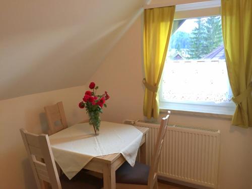 a table and chairs with a vase of flowers on it at Apartmaji in sobe Tina in Kranjska Gora