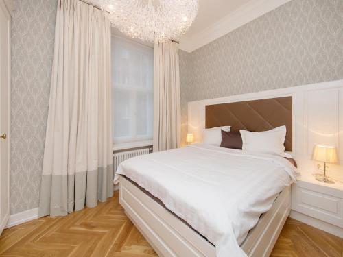 a bedroom with a large white bed and a chandelier at Harju Old Town Apartment in Tallinn