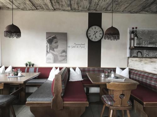 a restaurant with tables and a clock on the wall at Pension Spreitzhof & Appartement Royer in Schladming