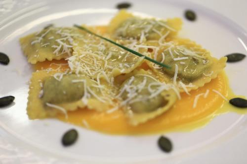 a white plate with a piece of pasta with cheese at Hotel Chalet Alaska in Pozza di Fassa