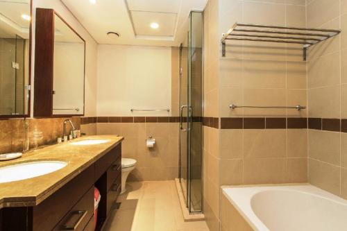 a bathroom with two sinks and a tub and a shower at Downtown Apartments with Fountain and Burj Khalifa View in Dubai