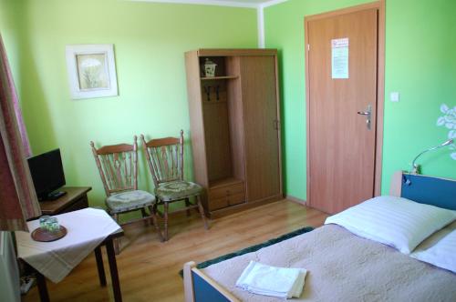 a bedroom with green walls and a bed and two chairs at Koral in Koszalin