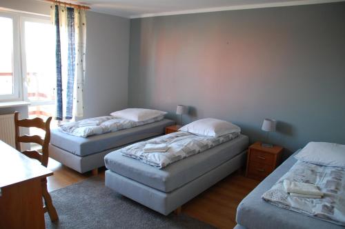 a room with three beds and a table and a window at Koral in Koszalin
