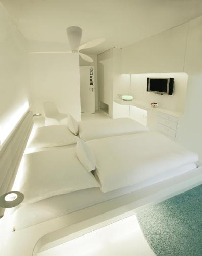a white bedroom with a bed and a tv at Vinotel Augustin in Sulzfeld am Main