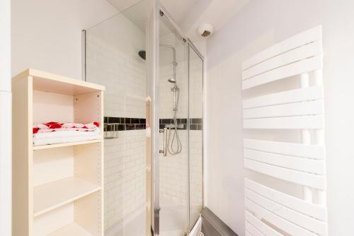 a white bathroom with a shower and a glass door at Le Patte d'Oie in Toulouse