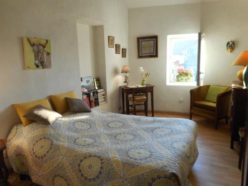 a bedroom with a bed and a chair and a window at Petit Grenier Douillet De Cathie in Roquemaure