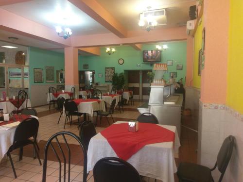 a restaurant with tables and chairs with red and white table cloth at Hoteles Santa Regina in Chihuahua