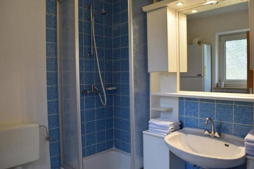 y baño de azulejos azules con lavabo y ducha. en Ferienpark Wehrda GmbH en Wehrda