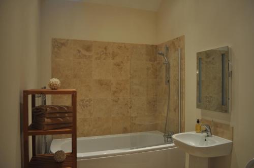 a bathroom with a shower and a sink and a tub at The Old Stables, Alltshellach Cottages in North Ballachulish