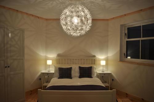 a bedroom with a bed and a chandelier at The Old Stables, Alltshellach Cottages in North Ballachulish