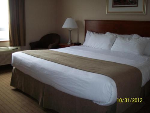 a hotel room with a large bed and a chair at Days Inn by Wyndham Moose Jaw in Moose Jaw