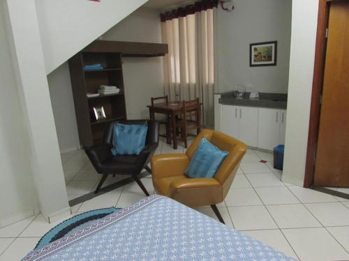 a bedroom with a bed and two chairs and a table at Pousada Beira Rio in Itumbiara