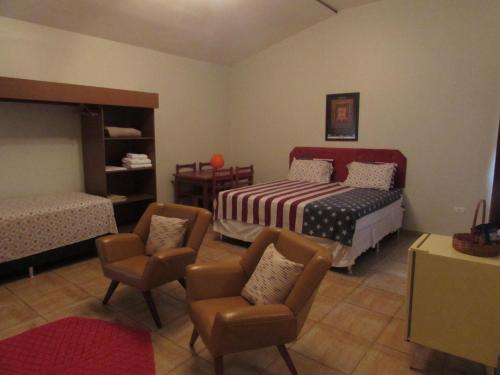 a bedroom with a bed and chairs in it at Pousada Beira Rio in Itumbiara