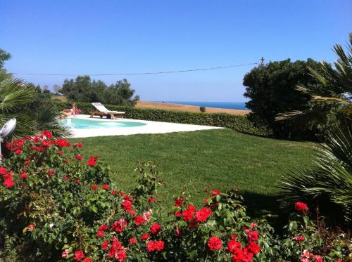 um jardim com flores vermelhas e uma piscina em Appartamento sulla Riviera del Conero em Numana