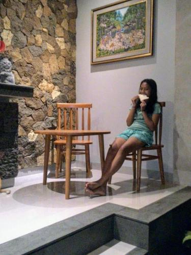 a woman sitting in a chair eating food at ThreeWin Homestay in Ubud