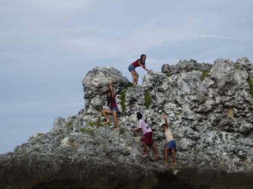 a group of people climbing on top of a rock at Guanna's Place Room and Resto Bar in Malapascua Island