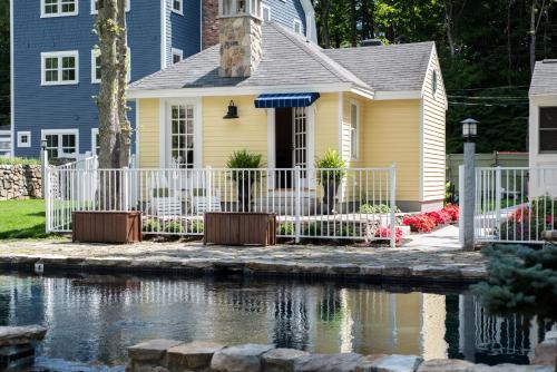 a yellow house with a white fence next to a pond at The White Barn Inn & Spa, Auberge Collection in Kennebunk