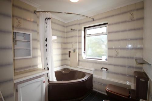 ein Bad mit einer Badewanne, einem Waschbecken und einem Fenster in der Unterkunft Hill Crescent in London