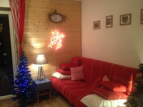 a living room with a red couch and a christmas tree at Romantic Chalet-Style Flat with Mountain View in Torgon