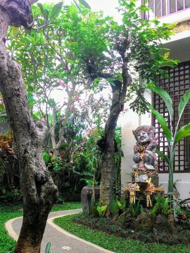 a statue of a bear sitting between two trees at ThreeWin Homestay in Ubud