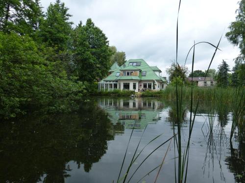 a house sitting on top of a body of water at Moderne Maisonette-Wohnung am Karpfenteich; modern Apartment with view of the carp pond in Barmstedt