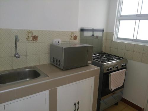 a kitchen with a sink and a stove at Strenua - Las Quintanas in Trujillo
