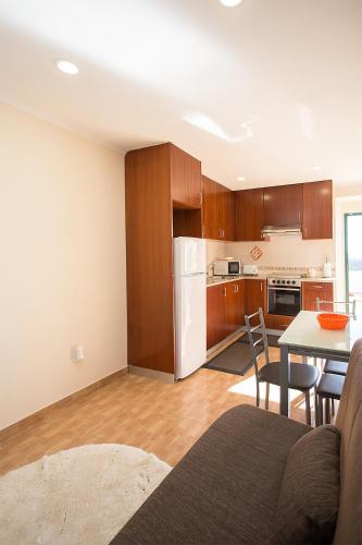 a kitchen with wooden cabinets and a table with chairs at CASAL RIQUEZO T1 - Serra da Pescaria - NAZARÉ in Nazaré