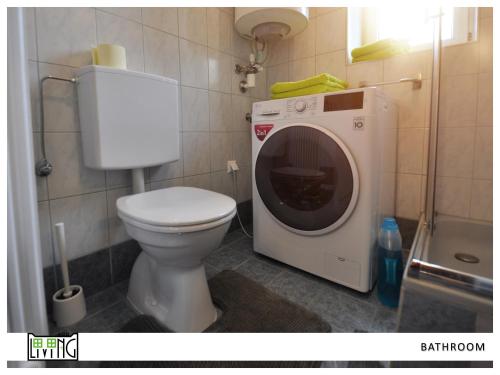 a bathroom with a toilet and a washing machine at ACO Living - A Cheap Overnight in Klagenfurt