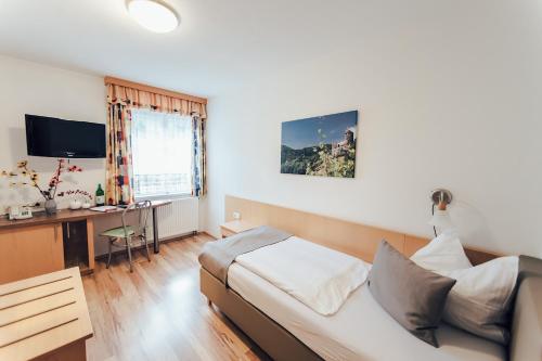 a bedroom with a bed and a desk and a television at Gästehaus Kleindienst in Deutschlandsberg