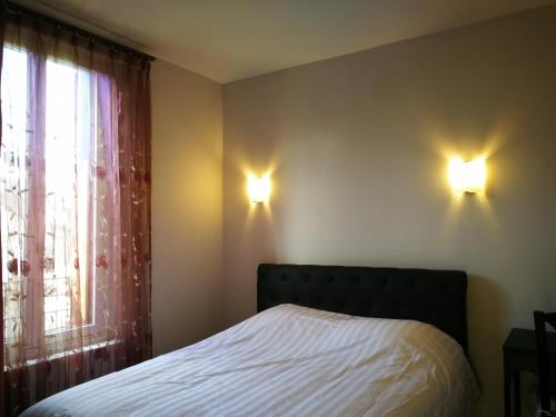 een slaapkamer met een bed en twee lampen aan de muur bij chambre noisy in Noisy-le-Sec