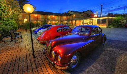 twee oude auto's geparkeerd op een parkeerplaats bij Cooma Motor Lodge Motel in Cooma